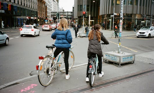 2 Mädchen warten mit dem Fahrrad an einer Ampel