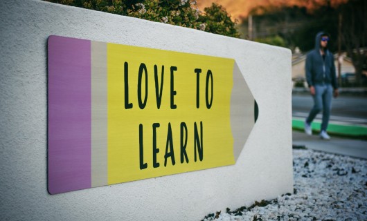 Schild in der Form eines Stiftes mit der Aufschrift: Love to learn.